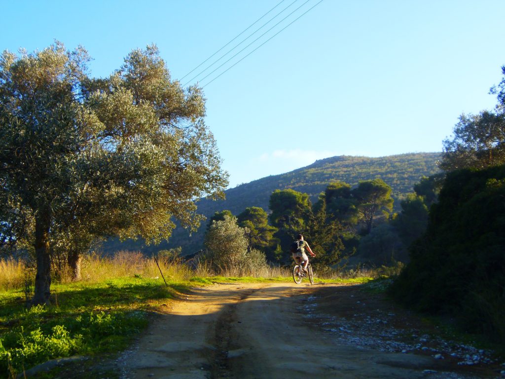 man cycles on a scenic country road in greece